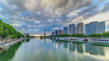 Eyfel Kulesi, Seine Nehri 'nde ve Fransa' nın Paris şehrinde teknelerle gün doğumu zamanı. Mirabeau Köprüsü 'nden gökyüzü dramatik bir şekilde görünüyor. Modern binalar ve yol trafiği. Özgürlük Anıtı