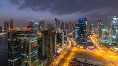 Dubai iş hangarı kuleleri hava gününden geceye geçiş zamanı. Bazı gökdelenlerin ve inşaat halindeki yeni kulelerin panoramik manzarası. Yolda trafik vardı.
