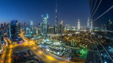 Dubai Şehir Merkezi 'nden geceye geçiş zamanı. Geceleri büyük, fütüristik şehir üzerinde hava manzarası. Dubai 'nin gökdelenleri camdan yansıyor, Birleşik Arap Emirlikleri. Akşam gökyüzü çatıdan yükseliyor