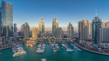 Dubai Marina gökdelenleri, hava zaman çizelgeleri, lüks yatları ve marina gezinti güvertesi olan liman, Dubai, Birleşik Arap Emirlikleri. Gölgeler gün batımında hareket eder