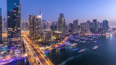 Dubai, BAE 'de gün batımından sonra yüzen yat ve teknelerle Dubai Marina gezinti güvertesi ve kanalı üzerinden geçen güzel bir gökyüzü çizgisi. Modern kuleler ve köprüdeki trafik.