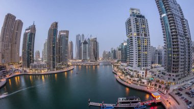 Hava üst görüntüsü, günden geceye geçiş zamanı. Dubai Marina gezinti güvertesi ve kanalı, gün batımından sonra Dubai, BAE 'de yüzen yatlar ve teknelerle dolu. Modern kuleler ve trafik