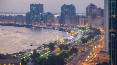 Dubai creek peyzaj gün gece geçiş timelapse tekneler ve yatlar ile ve trafik yol ve otopark ile modern binalar. Yukarıdan hava üstten görünüm
