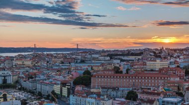 Lizbon, gün batımında, Portekiz 'in sonbahar akşamında şehir merkezinin kırmızı çatılı manzarası. Arkaplanda köprü var. Miradouro da Nossa Senhora do Monte bakış açısından üstten görünüm