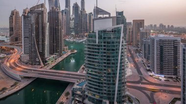 Dubai Marina yerleşim yerlerinin ve ofis gökdelenlerinin hava panoramik görüntüsü. Köprü ve rıhtımda gece gündüz trafik var. Gün doğumundan önce geçiş zamanı. Yüzen tekneler ve yatlar