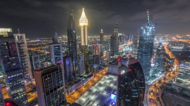 Dubai, BAE 'deki tüm gece boyunca Sheikh Zayed Yolu ve DIFC yakınlarındaki binaların panoramik silueti. Finansal merkezde ve şehir merkezinde aydınlık gökdelenler ve modern kuleler