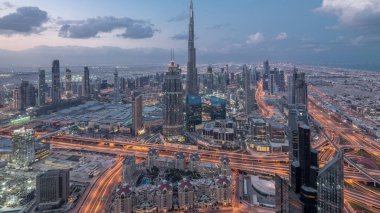 Dubai Şehir Merkezi 'nin gökdelenleri ve Burj Halife' nin gece gündüz gökdelenleri ile fütüristik şehir manzarası. Gündoğumundan önce çatıdan modern kuleleri ve inşaatı olan sabah manzarası