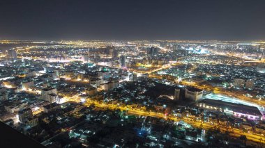 Panorama, Ajman 'ın çatıdan yola çıkan trafiği gece vakti aydınlık binalarda ışıkları olan şehir manzarasını gösteriyor. Birleşik Arap Emirlikleri.