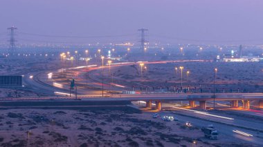 Gün batımından sonra Ajman 'dan Dubai' ye büyük bir şehirde, çöldeki karayolu trafiği günden geceye değişiyor. Ulaşım konsepti. Yukarıdan görüntüle