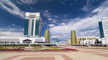 Nur-Sultan şehrinde Kazakistan Cumhuriyeti Senatosu 'nun inşa edilmesi. Ön planda çiçek açmış. Arka planda Nurzhol Bulvarı. Yazın mavi bulutlu gökyüzü