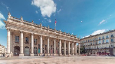 Büyük Bordeaux Tiyatrosu Fransa 'da zaman atlaması, Opera Ulusal ve Bale Ulusal' a ev sahipliği yapıyor. Sütunları olan neoklasik bir mimari mücevher. Mavi bulutlu gökyüzünün altında yürüyen insanlar
