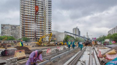 Gri inşaat teleskopik vinç beton plakalara zaman ayarlı tramvay raylarını boşaltıyor. Şapkalı ve üniformalı endüstriyel işçiler. Tramvay raylarının yeniden inşası