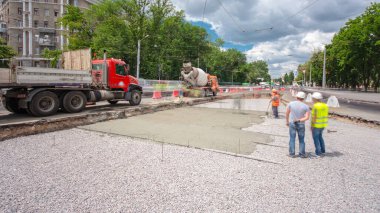 Tramvay rayları onarımı ve bakım zamanı olan bir yol inşaatı. Beton, kavşağın ortasında mikserle çalışıyor. Yeni toplu taşıma için demiryolu raylarının değiştirilmesi