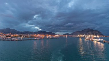 Gün batımından sonra açık denizde seyreden dalgalı ve limanlı deniz manzarası. Palermo kıyısı, İtalya