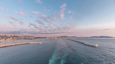 Gün batımında açık denizde yelken açan gemiden dalgalı ve limanlı deniz manzarası. Marsilya kıyısı, Fransa