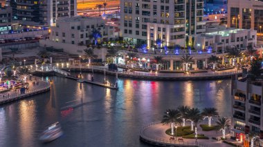 Geçen tekneler ve avuç içi gün gece ile promenade ile lüks Dubai Yat Limanı kanal timelapse geçiş, yukarıdan bakışta akşam güneş battıktan sonra Top. Dubai, Birleşik Arap Emirlikleri