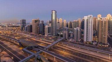 Dubai Yat Limanı gökdelenler hava üstten görünüm güneş doğmadan önce Jlt gelen Dubai gece gün timelapse, Birleşik Arap Emirlikleri için. Işıklı modern kuleleri ve Şeyh zayed yolu üzerinde trafik.