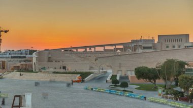 Katara Kültür Köyü 'nde günbatımı zaman dilimi olan amfitiyatro, Doha Katar. Havadan görünüşlü. İnsanlar çeşmenin önünde yürüyor.