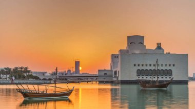Katar 'ın Doha kentindeki İslam Sanatları Müzesi yakınlarındaki günbatımında, arkasında yükselen gökdelenler görülüyor. Öndeki eski tekneler.