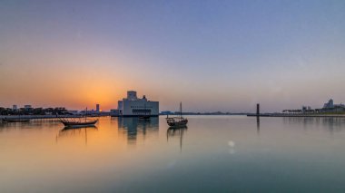 Katar 'ın Doha kentindeki İslam Sanatları Müzesi yakınlarındaki günbatımında, arkasında yükselen gökdelenler görülüyor. Öndeki eski tekneler.