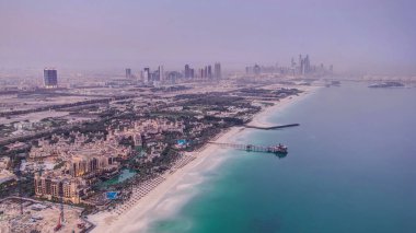 Dubai 'deki Dubai marina gökdelenlerini ve BAE' deki plajları gece gündüz gösteren gökyüzü görüntüsü. Helikopter pistinden hava manzarası