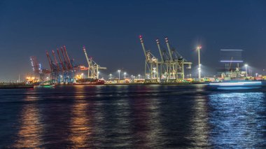 Hamburg kargo limanının gece tarifesi, Elbe Nehri 'nde konteynır terminalleri, vinçler ve kargo gemileri. Tekneler ve gemiler geçiyor ve dinamik bir deniz manzarası yaratıyorlar. Almanya