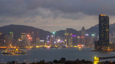 Hong Kong 'dan gece geçişi, Kowloon Körfezi' nden hava görüntüsü şehir merkezindeki zaman dilimi büyük gemi ve çatıdaki kuleler.