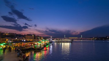 İstanbul 'un İstanbul silueti, gün batımından sonra İstanbul' da, İstanbul Boğazı 'ndaki Golden Horn' da tekne istasyonu yakınlarındaki yolcu feribotları. Arka plandaki cami ve köprü bahar günündeki su yansıması ile