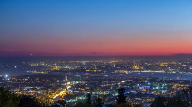 Istanbul night skyline scenery day to night transition timelapse, aerial view over Bosporus channel from Camlica hill. Blue water of Bosporus channel with ship. Traffic on roads