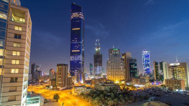 Kuveyt Şehri gökdelenleri ile gün batımından sonra gün batımından gün batımına kadar aydınlanan şehir merkezindeki geçiş zamanı. Çatıdan hava görüntüsü. Orta Doğu.