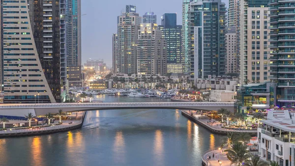 Dubai, BAE 'de gün batımından sonra yüzen yat ve teknelerle Dubai Marina gezinti güvertesi ve kanallarının havadan zamana güzel bir görüntüsü var. Modern kuleler ve yoldaki trafik.