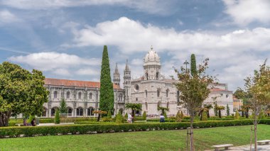 Mosteiro dos Jeronimos ve bahçede çimenliği olan yeşil ağaçlar, Lizbon, Portekiz 'in Belem bölgesinin zaman diliminde yer almaktadır. Manueline tarzı (Portekizce geç Gotik). Mavi gökyüzünde bulutlar