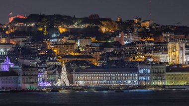 Lizbon Ticaret Meydanı 'nın Noel zamanı aydınlandı. Turistler, açılış ışık gösterisi sırasında parlayan ağacın ve dekorasyonların etrafında toplanıyorlar. Portekiz 'in başkentinde ikonik gece sahnesi