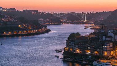 Day to night transition aerial view of the historic city of Porto, Portugal panoramic timelapse from the Dom Luiz bridge. Illuminated waterfront and curved river from above