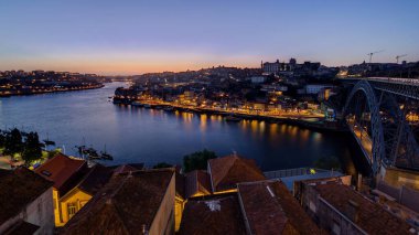Panorama old city Porto at river Duoro, with Port transporting boats day to night transition timelapse with the Arrabida bridge after sunset, Oporto, Portugal