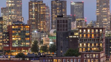 Rotterdam, Hollanda 'daki Katendrecht yarımadası ve Maashaven limanının hava ve gece geçiş zamanı. Günbatımından sonra parlayan pencereleri olan modern gökdelenler.