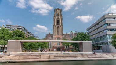 Laurenskerk 'in (Saint Lawrence Kilisesi) Grotekerkplein, Rotterdam' daki hiperlapesi. İnsanlar mavi bulutlu gökyüzünün altında çimlerde dinleniyorlar. Kanal merdivenlerinin yanında saati olan tarihi çan kulesi. Hollanda