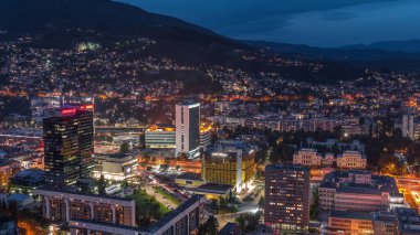 Saraybosna 'nın güney kesiminin gündüz ve gece hava görüntüsü. Gökdelenleri ve dağları olan gökdelenler. Gün batımından sonraki en yüksek kuleden. Bosna-Hersek ve Güneydoğu Avrupa.