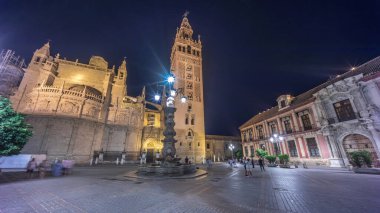 La Giralda ve Seville Katedrali geceleri aşırı hızlanarak altın ışıklarla parıldıyor. Tarihi çan kulesi, gotik detaylar ve aydınlatılmış sokaklar Sevilla, İspanya 'da büyülü bir atmosfer yaratıyor.