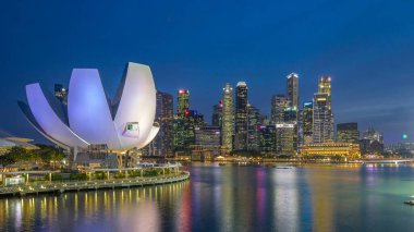 Futuristic architecture flower shape design of the Art Science museum day to night transition timelapse after sunset. Skyscrapers skyline city of Singapore.