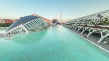 Valencia 'nın Sanat ve Bilim Şehri' nin çarpıcı zamansal hızlandırıcı gölgeleri fütüristik mimari üzerinde hareket ederken sakin suya yansıyor. Günbatımında büyüleyici İspanyol kültürel simgesi