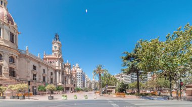 Panorama, Plaza de Ayuntamiento 'da Valencia Belediye Binası' nı (Ajuntament de Valencia) gösteriyor. Mavi gökyüzünün altında saat kulesi olan tarihi bir bina. İspanya 'nın ana meydanında gezinen insanlar
