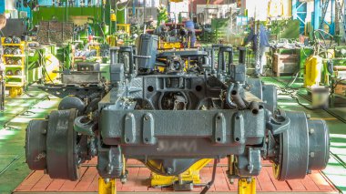 Konveyör montajı, traktörün gövdesini büyük endüstriyel fabrika zaman diliminde sahneleyecek. Çerçeve montajı, Chassis kurulumu ve diğer bölümler etrafındaki işçiler.