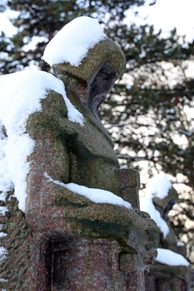 sculptures of warriors with swords covered with snow at municipal cemetery in Amsterdam, The Netherlands