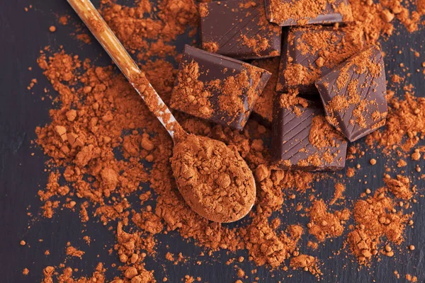 Broken dark chocolate with cocoa powder — Stock Photo, Image