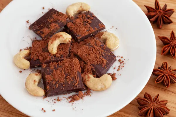 Chocolate escuro quebrado com cacau em pó e castanha de caju e estrela — Fotografia de Stock