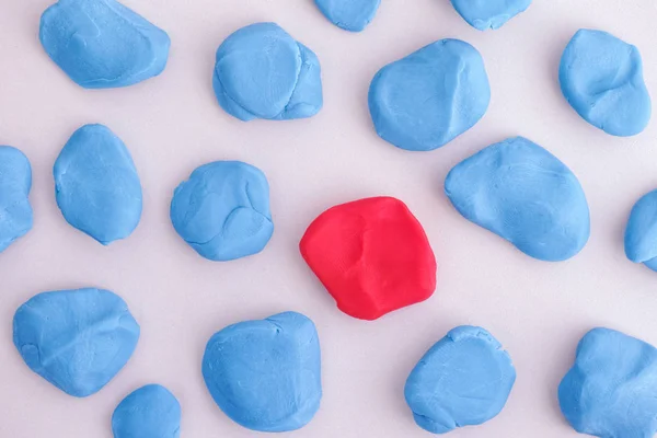 Blue plasticine pieces around a red one — Stock Photo, Image