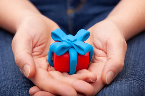 Woman holds gift wrapped with blue ribbon — Stock Photo, Image