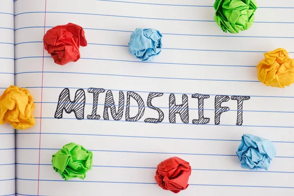 Word Mindshift на аркуші ноутбука з різнокольоровими збитими паперовими кульками навколо нього — стокове фото