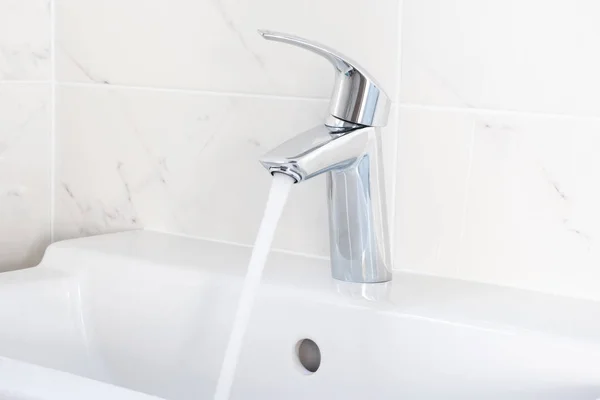 Faucet pouring water into sink — Stock Photo, Image